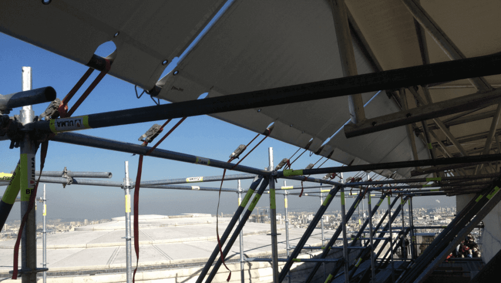Installation d'une bâche parapluie en utilisant les fourreaux et les tubes d'échafaudage.